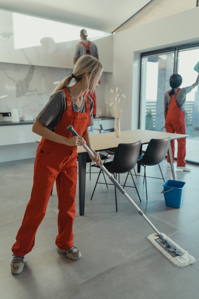 services-02 Cleaning team in red overalls mopping and sanitizing a modern home interior.